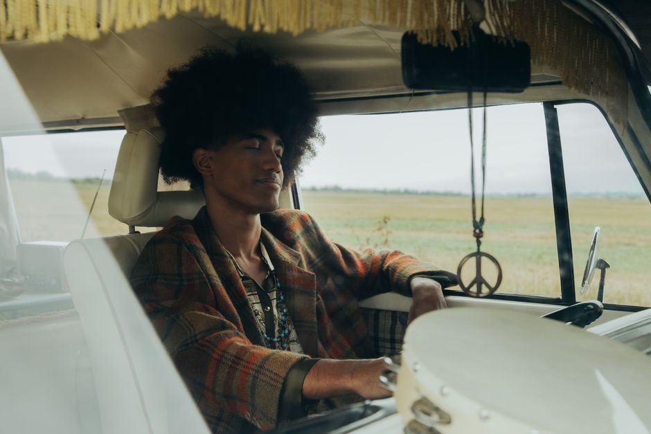 A retro-styled young man driving a vintage hippie van, evoking the groovy vibe of slang like "dig it" from before 1980.
