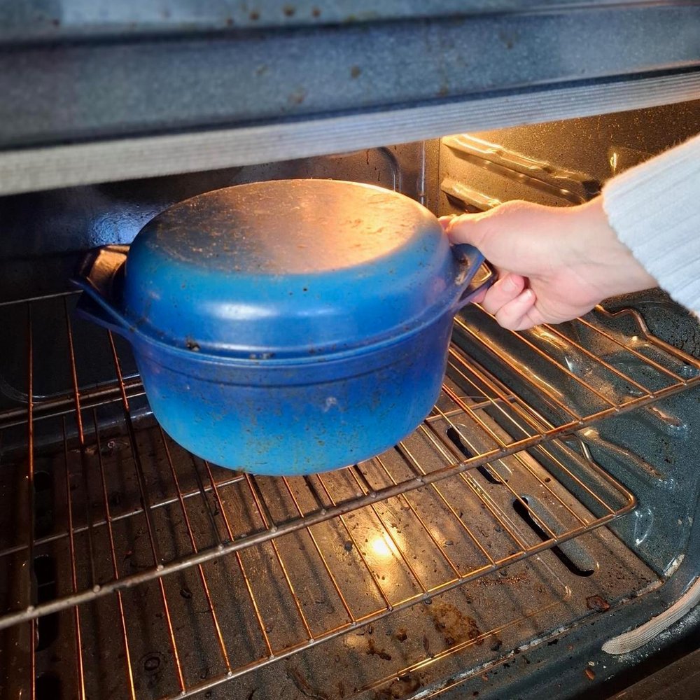 A blue Dutch oven going into the oven