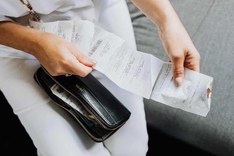 Woman sorting through old paper receipts and coupons cluttering her purse.