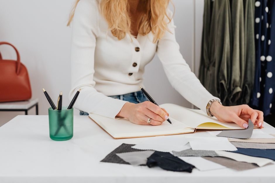 A woman writes in a notebook beside a cup full of pens, illustrating the difference between a handful of useless pens and one that actually works.