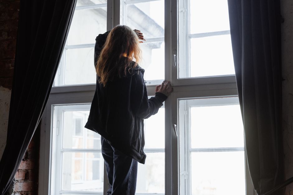 A person reaching toward the light through a window, symbolizing hope that hard phases eventually end.