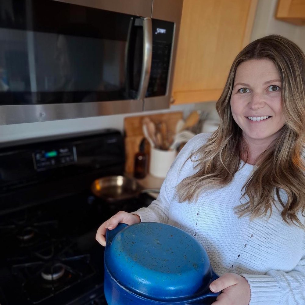 Isabel Bernard in her kitchen holding a blue Dutch oven