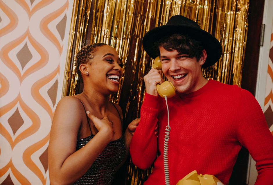 Two friends laughing and chatting on a retro phone, evoking the fun, old-school slang vibe of calling someone a 'jive turkey.'