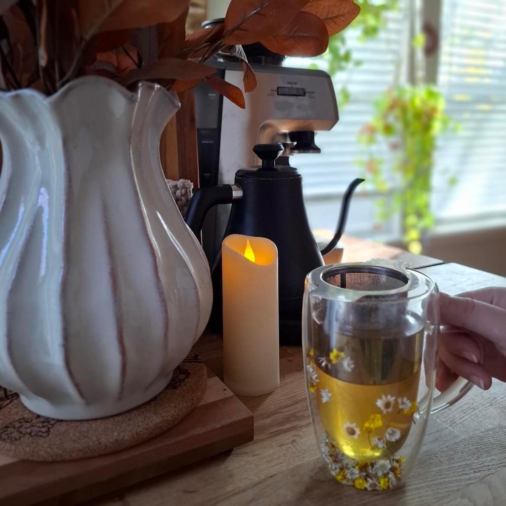 A glass mug of loose leaf tea steeping on the counter