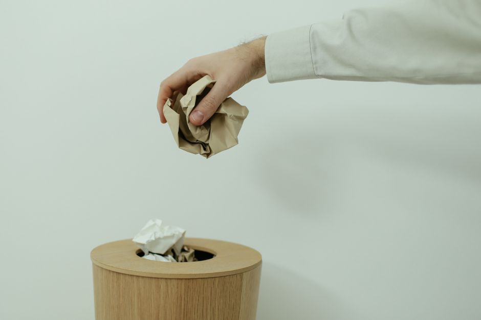 Tossing a crumpled receipt into the trash bin where it belongs.