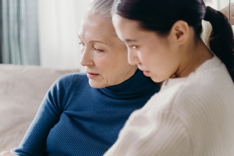 A daughter sits close to her mother, having a heartfelt conversation about her family history.