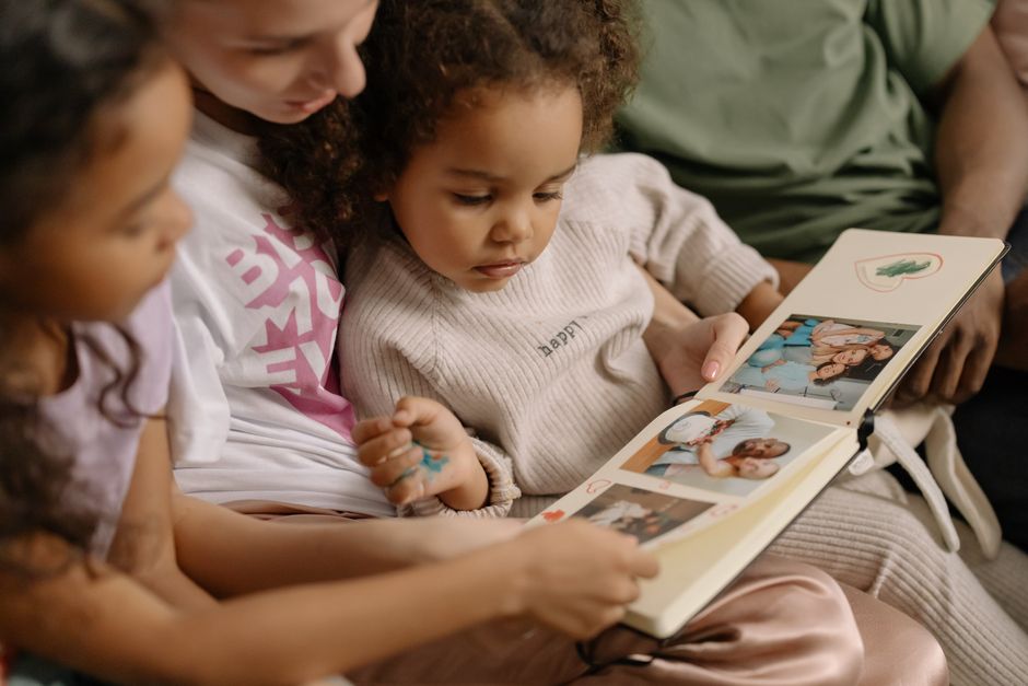 Family members browsing an old photo album together, reminiscing about baby pictures.