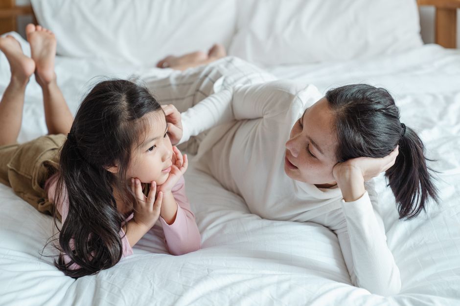 Mother and daughter lying on a bed having a heartfelt conversation, reminiscent of asking mom about her dreams before becoming a parent.