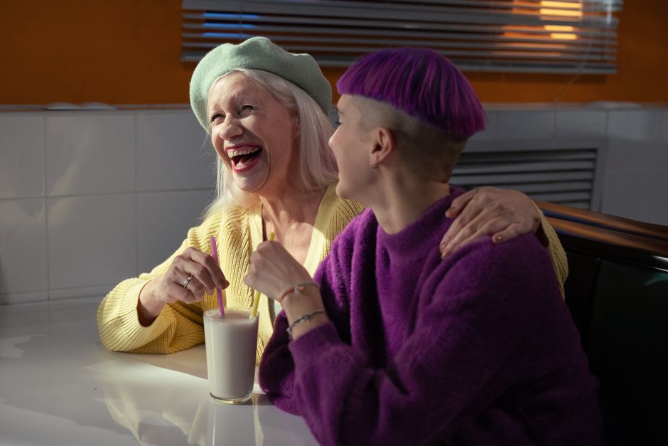 A mother laughing and sharing a close, joyful moment with a friend, reminiscent of cherished friendships worth asking about.