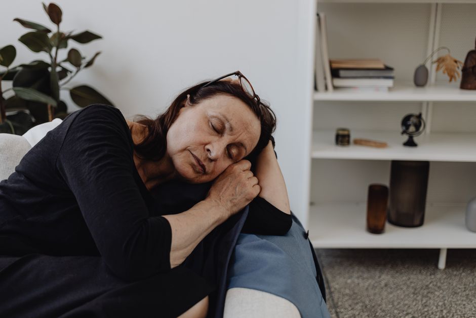 An older woman enjoys a peaceful afternoon nap curled up on a comfortable chair.