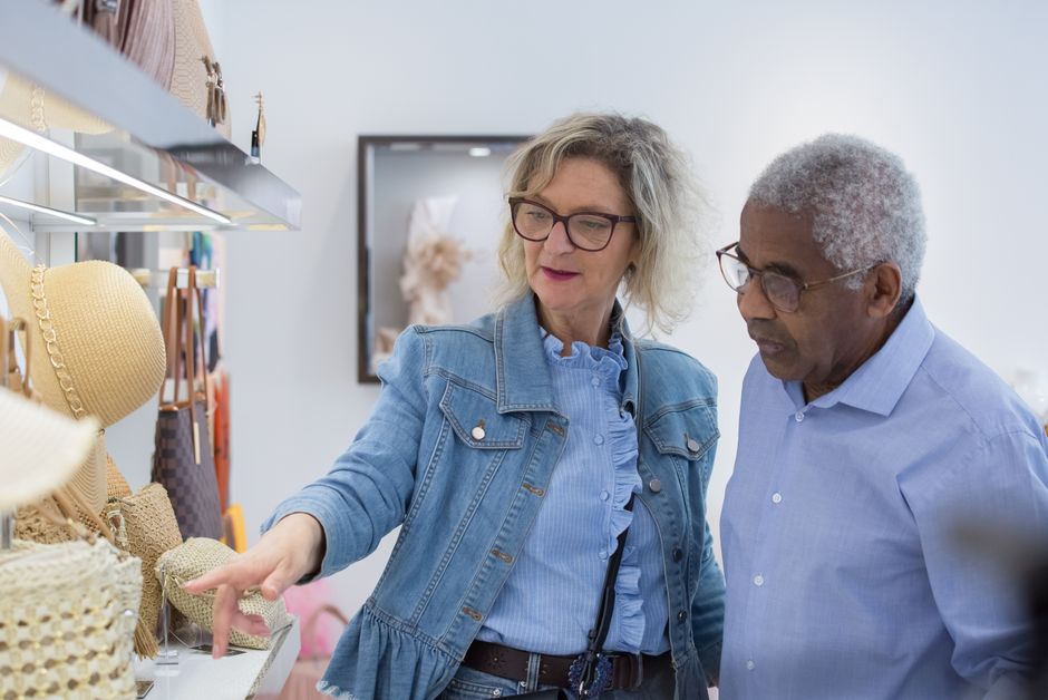 Older couple carefully inspecting a quality, well-made item in a shop, choosing durability over frequent purchases.