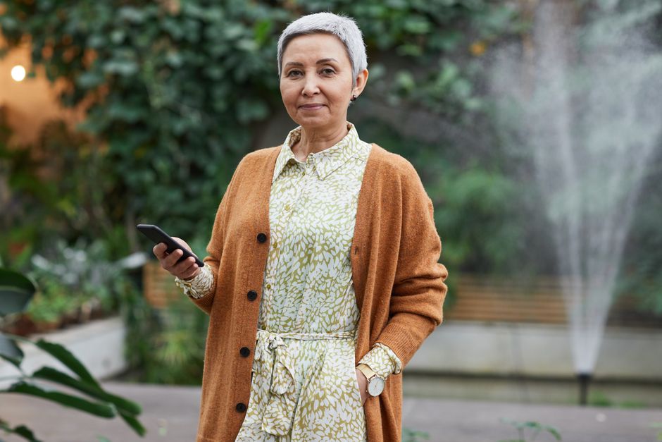 An older woman confidently wears her cardigan sweater outdoors, proving that carrying a sweater everywhere really is just good planning.
