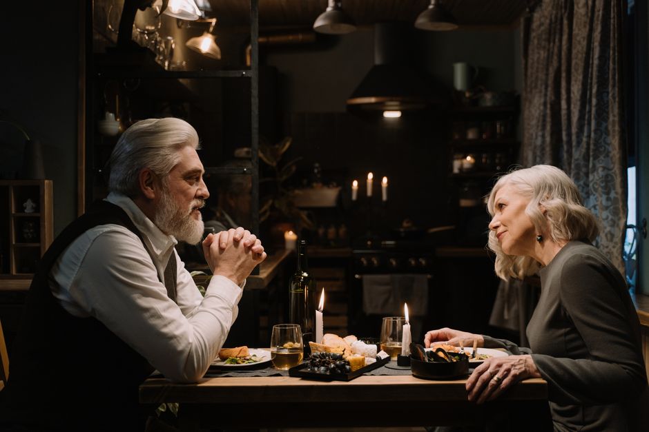 An older couple enjoying a calm, candlelit dinner together, reflecting the kindness that comes from eating early and unhurried meals.