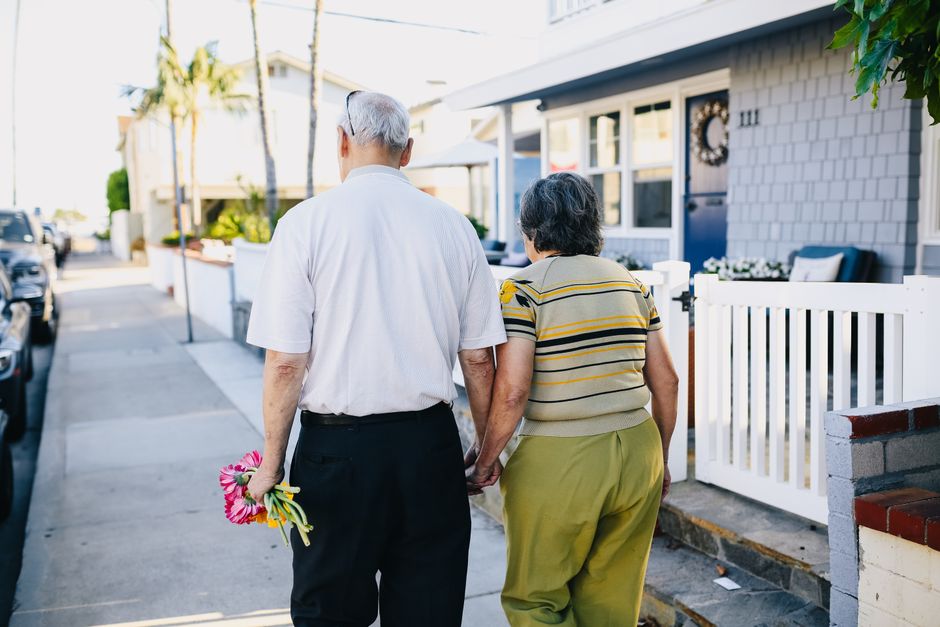 An elderly couple takes their evening walk together through the neighborhood after dinner.