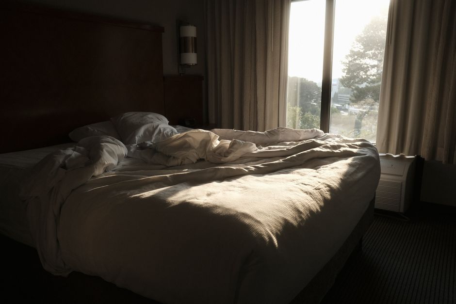 Sunlight pours over an empty bed in the early morning, capturing the quiet hour gained by waking up early.