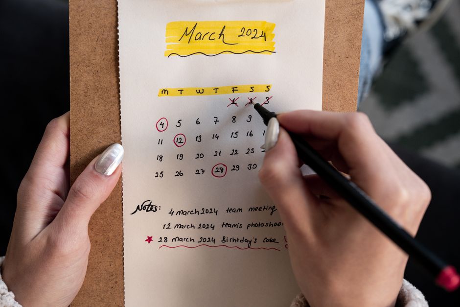 A paper calendar marked with important dates and notes, the kind of old-school habit that helps avoid household scheduling conflicts.