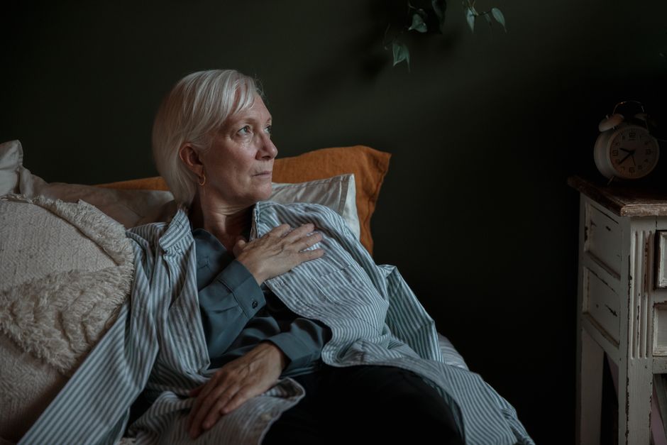 Older woman relaxing peacefully in bed at night, having chosen to stay in instead of going out.