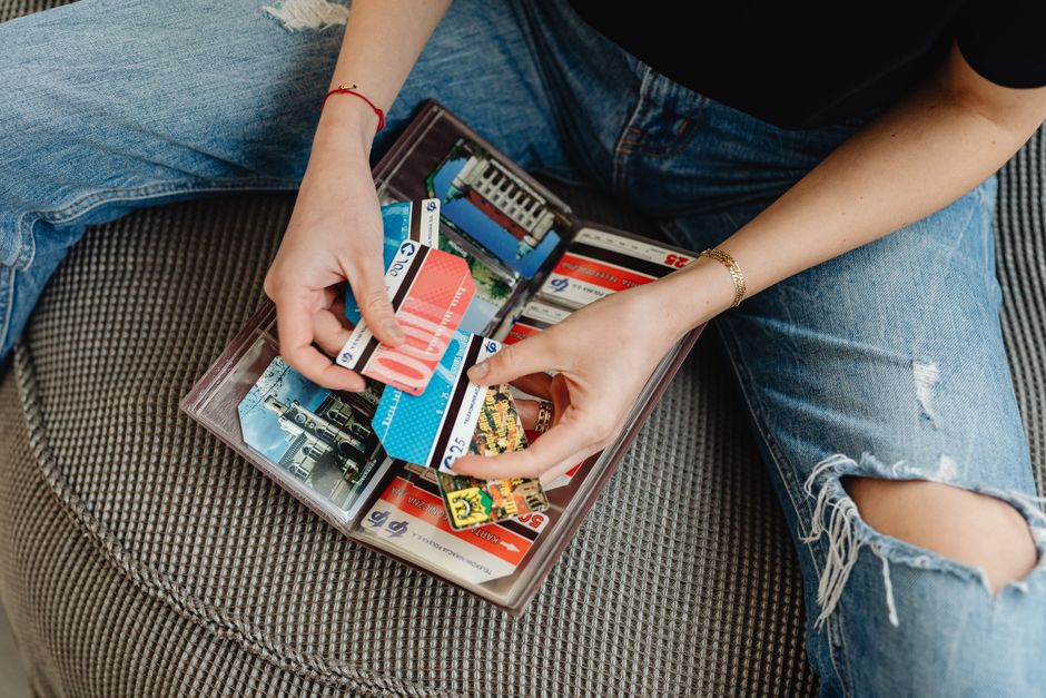 Sorting through a cluttered stack of old punch cards for places rarely visited, taking up unnecessary space in a purse.
