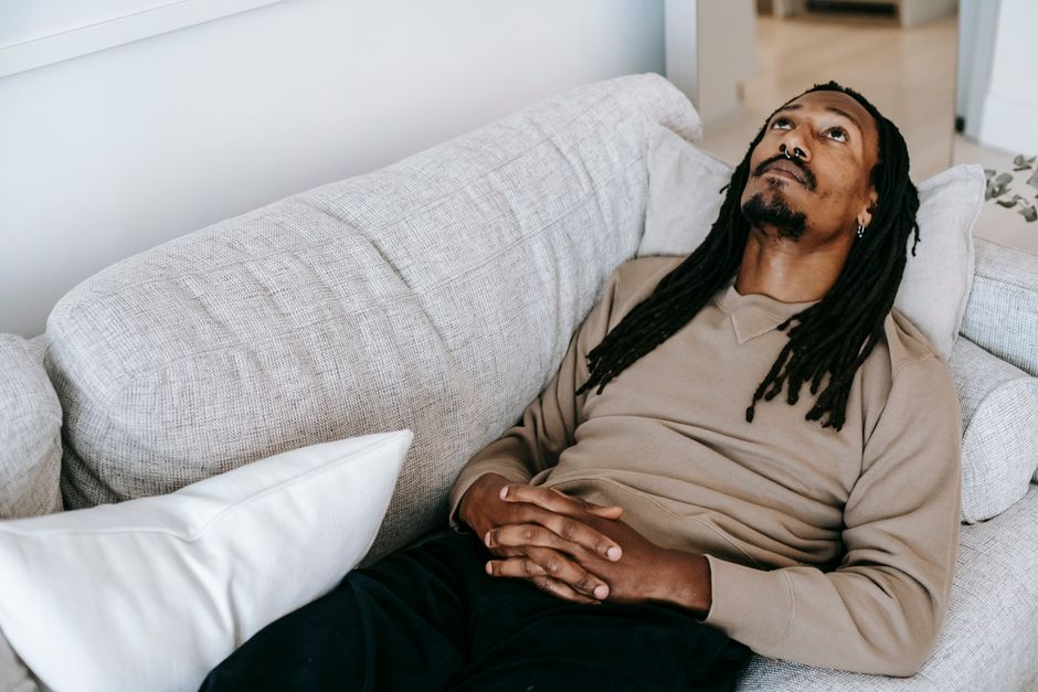 Man relaxing on a couch, staring thoughtfully into space, reflecting on life's quiet wisdom.