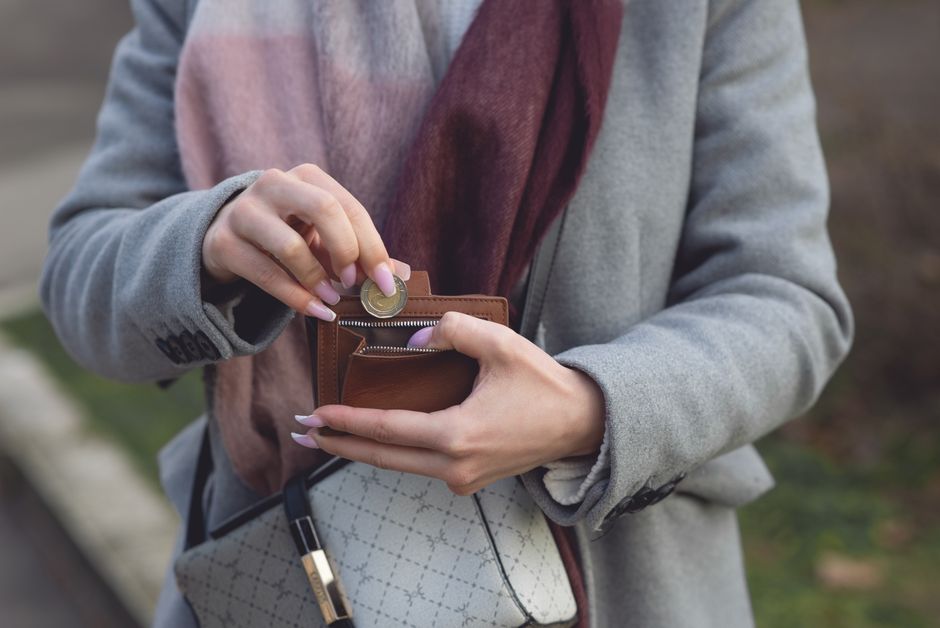 Woman retrieving a coin from a small wallet tucked inside her purse, keeping a bit of cash handy.