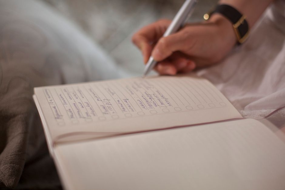 Person writing a daily checklist in a journal, symbolizing the small daily promise to oneself.