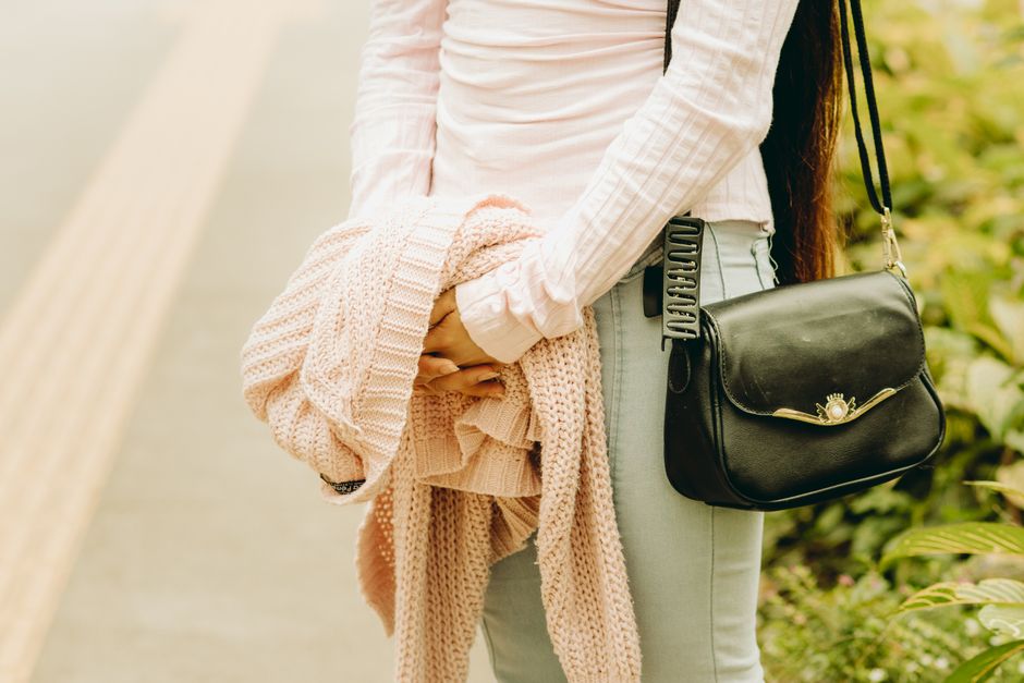A woman carrying a crossbody purse outdoors, representing what belongs in a practical handbag.