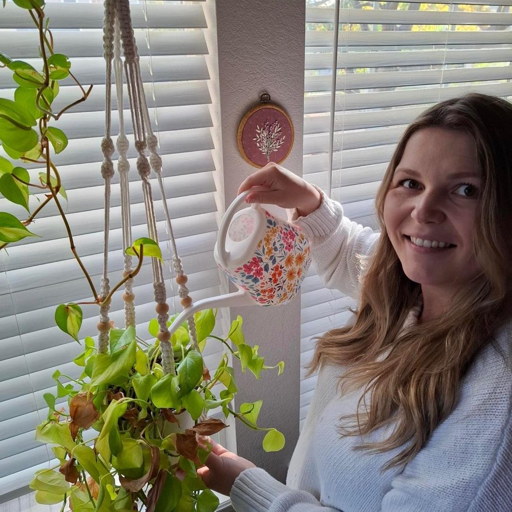 Isabel watering the pothos plant by her kitchen window