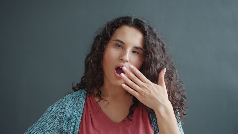 A woman yawning from boredom, illustrating the retro slang term "what a drag" for something tiring or dull.