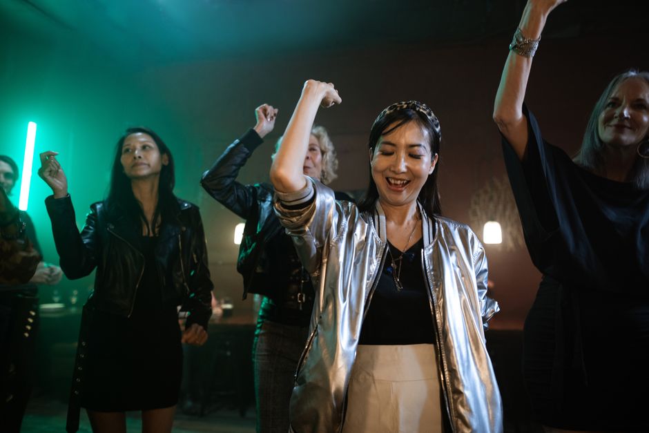 Women of different ages dancing energetically on a club dance floor at night.